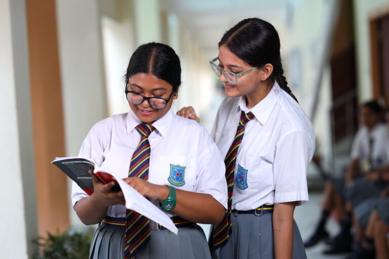 Two girl students reading in the hallway